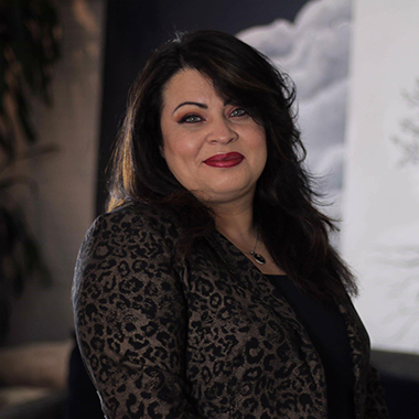 Creative Director Cynthia Arevalo posing for the camera wearing a leopard print jacket and blurry background